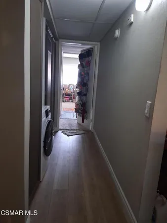 a view of a hallway with wooden floor and a bathroom