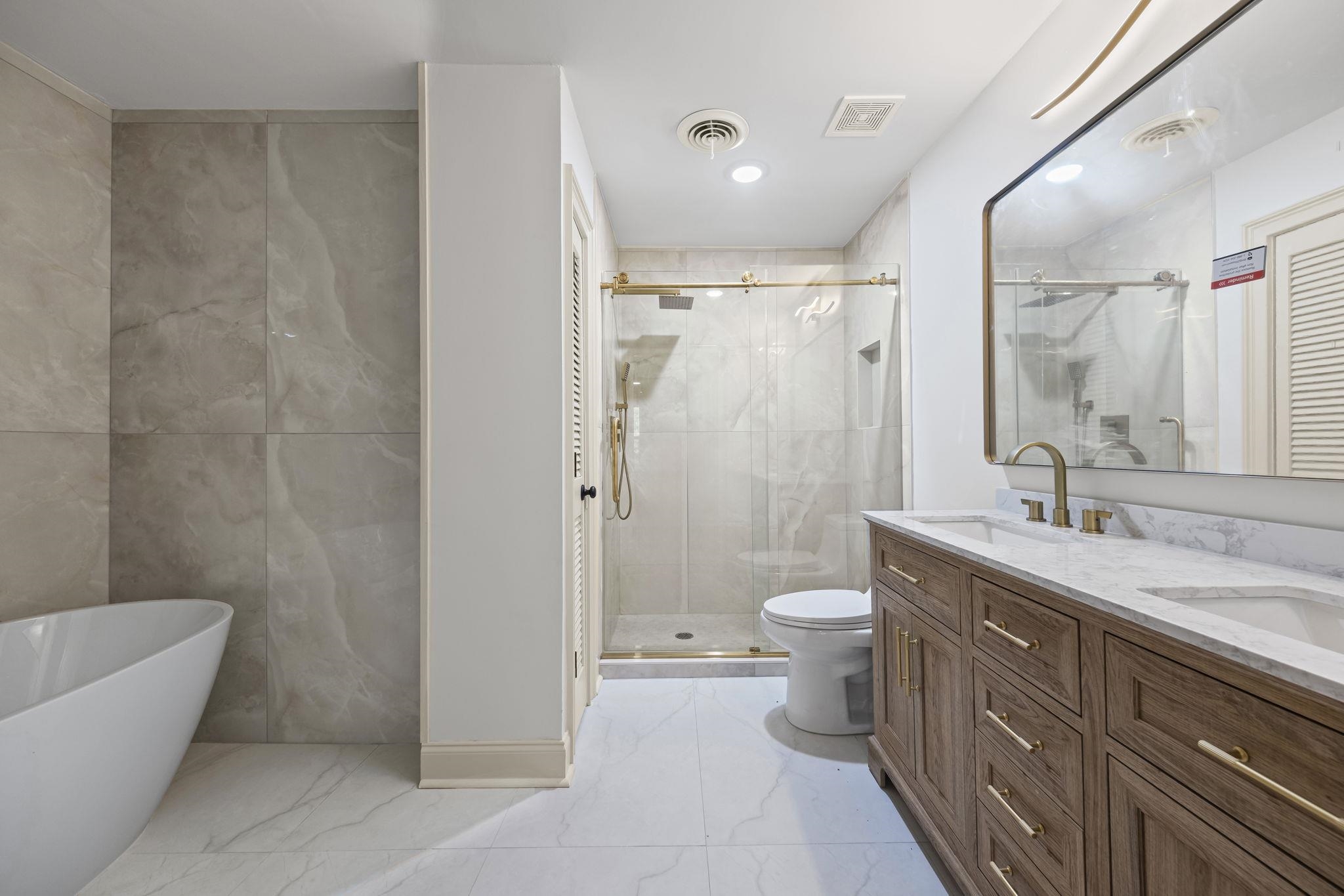 7086 McVay Road Germantown, TN 38138 - Photo 35 of 40 Primary bathroom with a stall shower, double vanity, tiled floors, a soaker tub, linen closet, tile walls