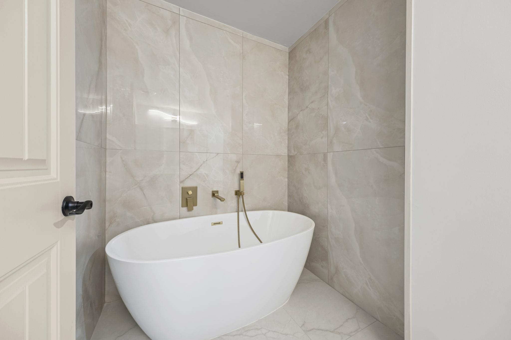 7086 McVay Road Germantown, TN 38138 - Photo 36 of 40 Bathroom featuring tile walls, a freestanding tub, and tiled floors