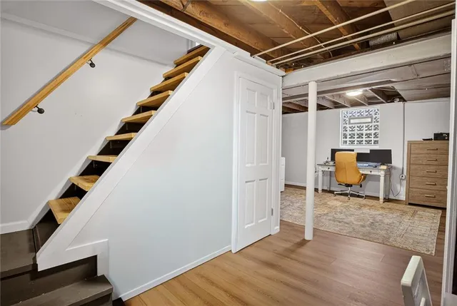 a view of an empty room with wooden floor and stairs