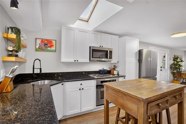 a kitchen with stainless steel appliances granite countertop a stove a sink dishwasher and a refrigerator with wooden floor