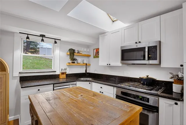 a kitchen with stainless steel appliances a stove microwave and sink
