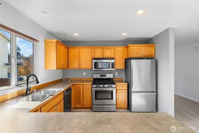 a kitchen with stainless steel appliances granite countertop a refrigerator a sink a stove and island