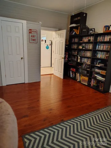 a view of empty room with wooden floor and book shelf