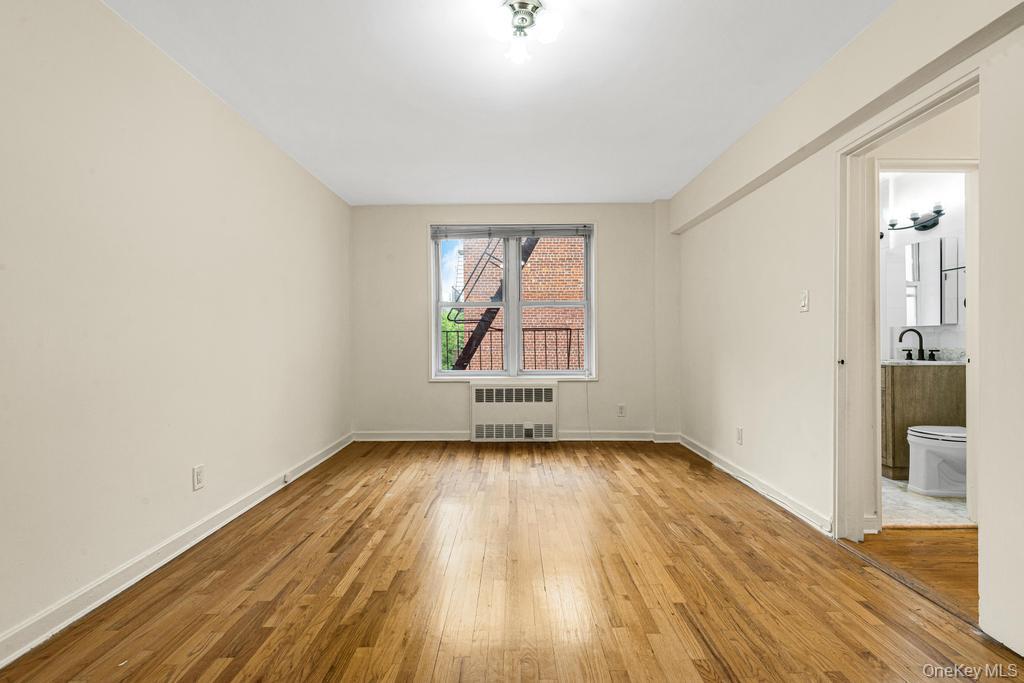 72-10 112th Street, Unit 5B Queens, NY 11375 - Photo 23 of 27 an empty room with wooden floor and windows