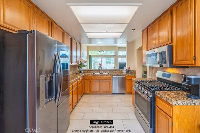 a kitchen with stainless steel appliances granite countertop a refrigerator a stove and a sink