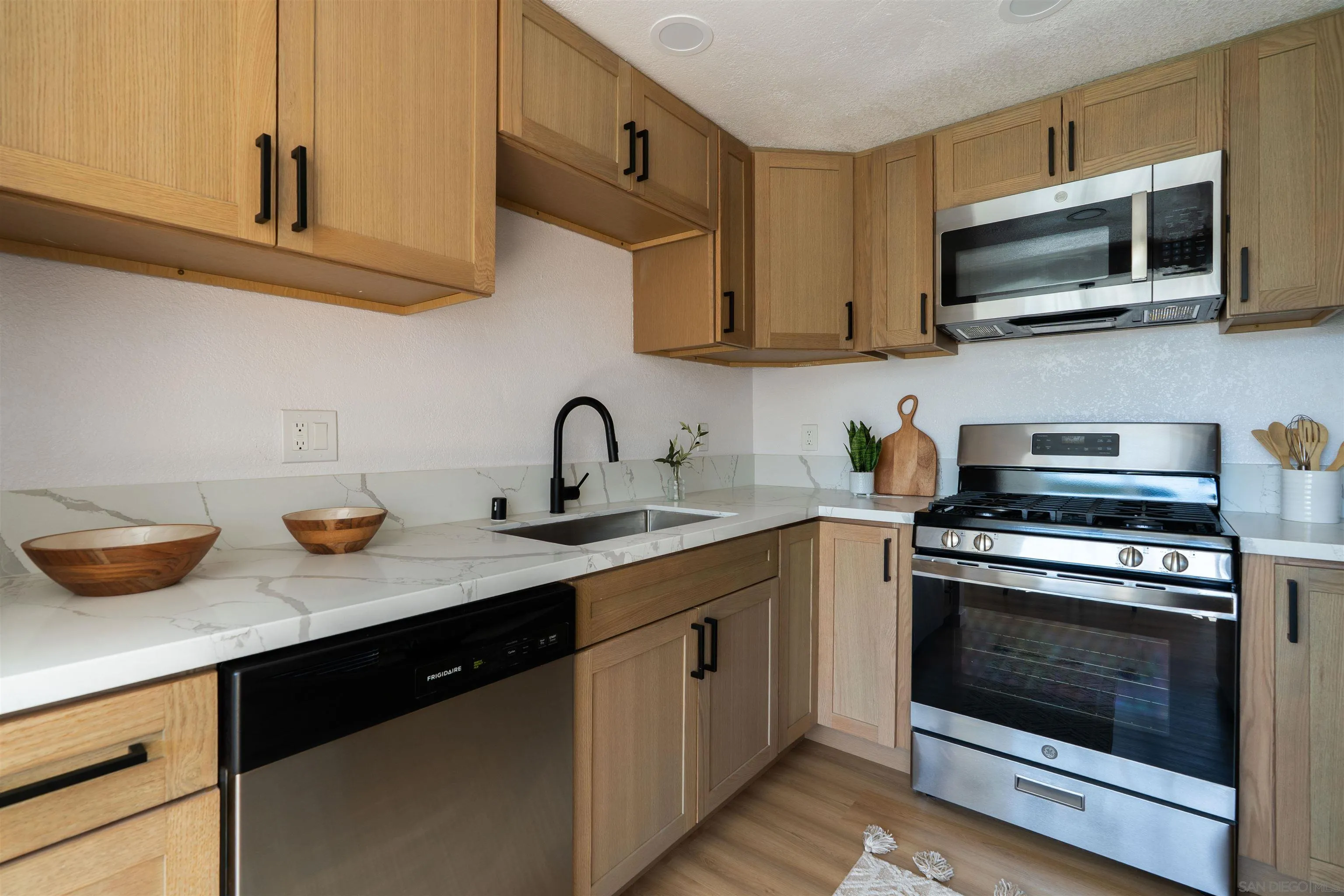 3101 King Arthurs Court Spring Valley, CA 91977 - Photo 20 of 40 a kitchen with stainless steel appliances granite countertop a sink a stove top oven and wooden cabinetry