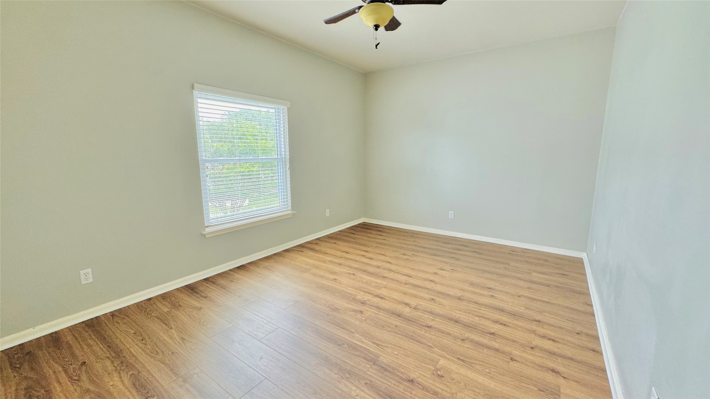401 Witte Road Kyle, TX 78640 - Photo 8 of 9 Bedroom 3-A well-lit bedroom with appealing wood-look flooring and a functional ceiling fan.
