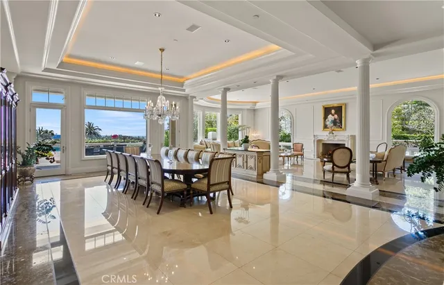 a view of a dining room and livingroom with furniture wooden floor a fireplace and a chandelier