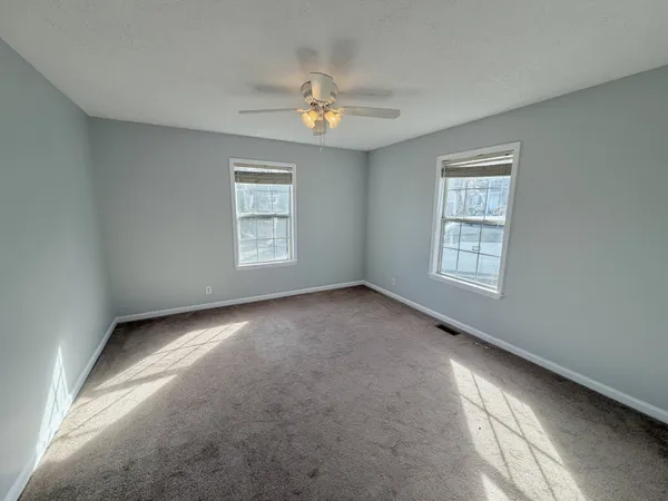 an empty room with windows and chandelier fan