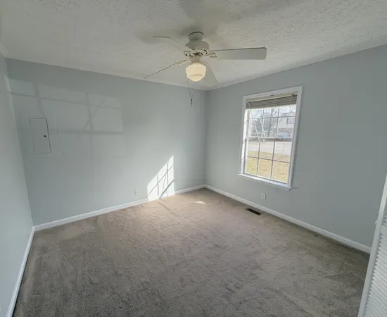 an empty room with windows and fan