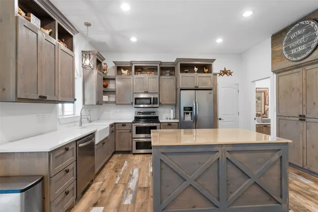 a large kitchen with stainless steel appliances granite countertop a lot of counter space and wooden floors