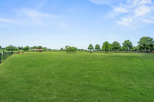 a yard with lots of green space and trees in the background