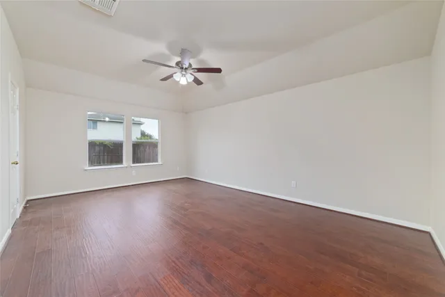 a view of empty room with wooden floor and ceiling fan