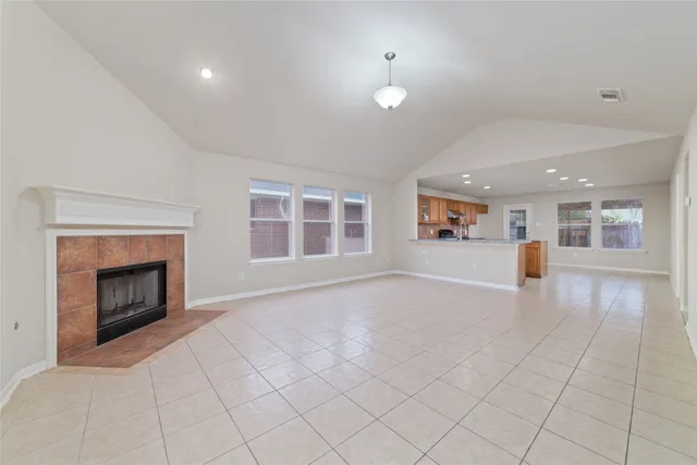 an empty room with windows and fireplace
