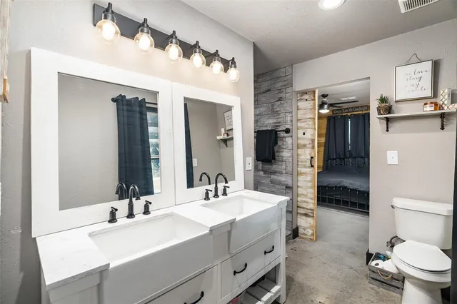 a bathroom with a sink double vanity granite and a toilet