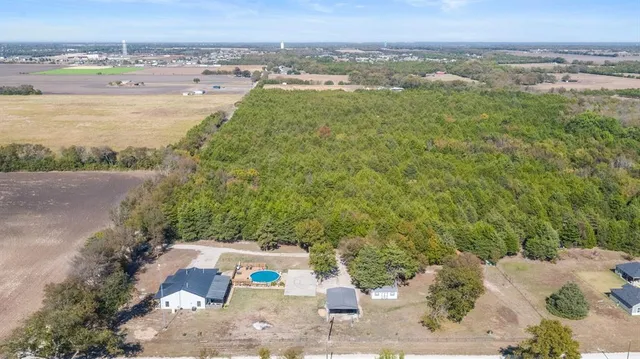 an aerial view of a residential houses with outdoor space and trees