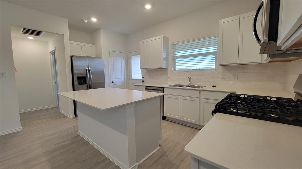 587 Avre Loop Kyle, TX 78640 - Photo 4 of 20 a kitchen with a sink a stove a refrigerator and cabinets