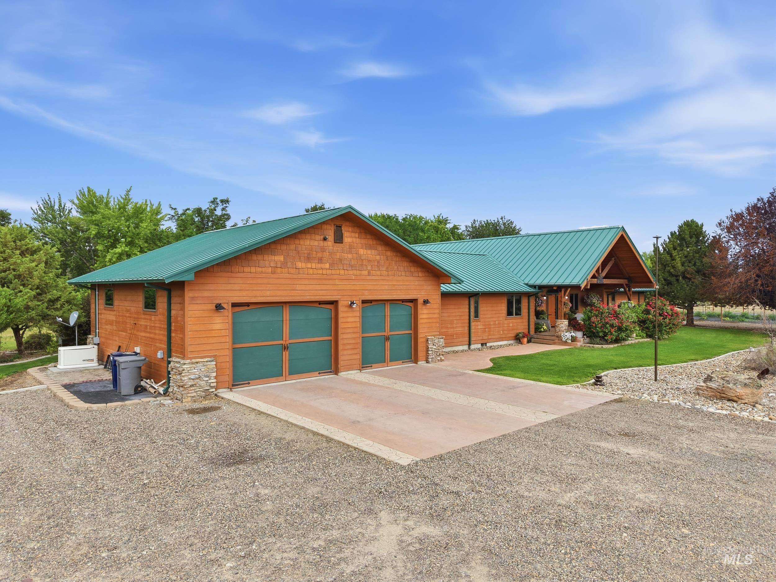339 Airport Road Weiser, ID 83672 - Photo 3 of 49 Wood-sided ranch-style home featuring a green metal roof and a prominent two-car garage