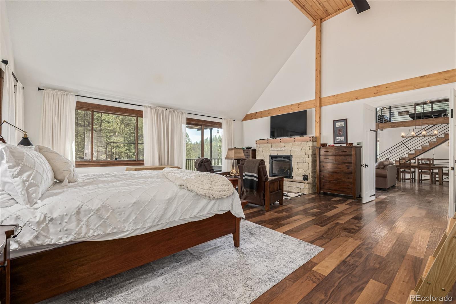 663 Brookside Drive Bailey, CO 80421 - Photo 18 of 47 a spacious bedroom with a large bed a flat tv screen and a fireplace