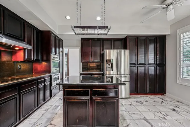 a kitchen with stainless steel appliances kitchen island granite countertop a refrigerator and a stove top oven