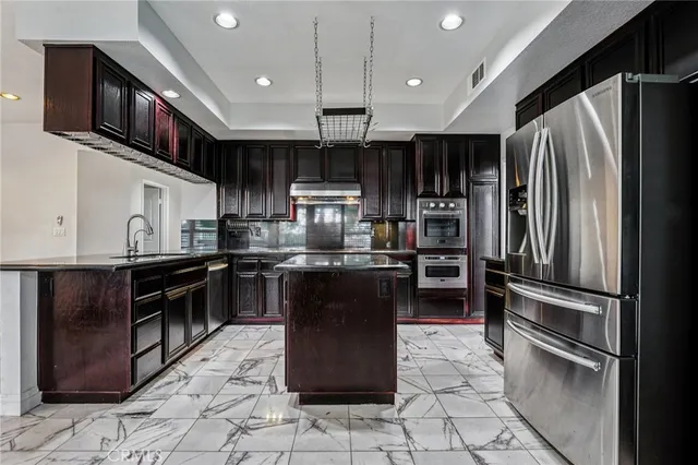 a kitchen with stainless steel appliances granite countertop a refrigerator a stove a sink and a microwave