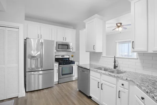 a kitchen with granite countertop stainless steel appliances a refrigerator cabinets and wooden floor