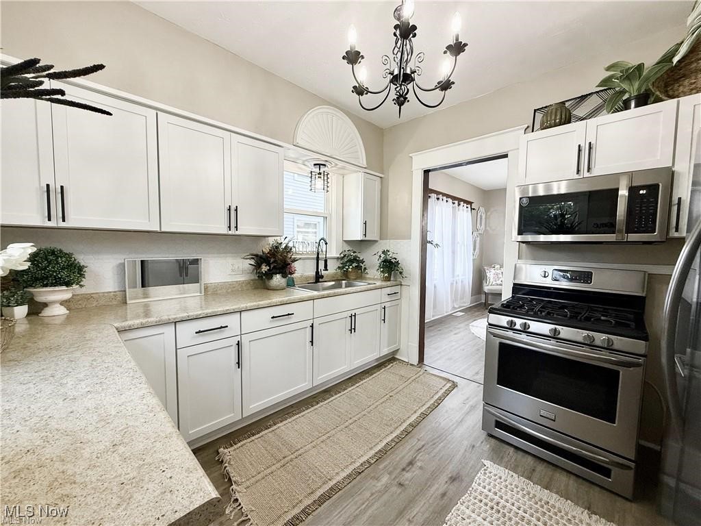 281 Sexton Street Struthers, OH 44471 - Photo 11 of 28 Kitchen featuring stainless steel appliances, white cabinets, hanging light fixtures, light wood finished floors, and a chandelier