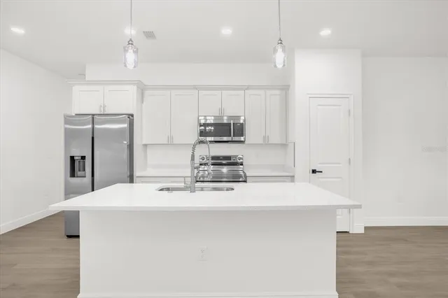 a kitchen with kitchen island a sink stainless steel appliances and cabinets