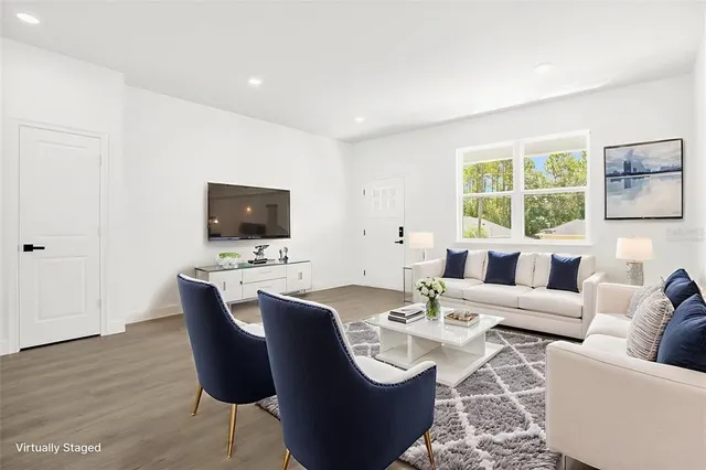 a living room with furniture a flat screen tv and a window