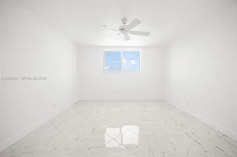 an empty room with a window and a ceiling fan