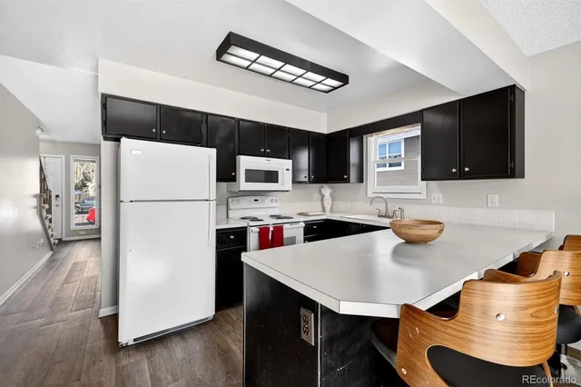 a kitchen with stainless steel appliances a refrigerator a stove a microwave a dining table and chairs