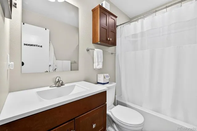 a bathroom with a sink a toilet a mirror and shower curtain