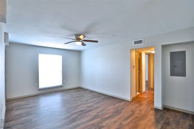 an empty room with wooden floor cabinet and windows