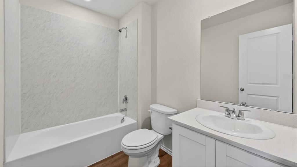 3534 Spring Time Street Forney, TX 75126 - Photo 24 of 24 Bathroom featuring a white bathtub, integrated shower, white vanity with an undermount sink, a large wall-mounted mirror, and wood-finish flooring