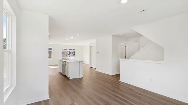 a kitchen with stainless steel appliances a stove a sink a refrigerator white cabinets and wooden floor