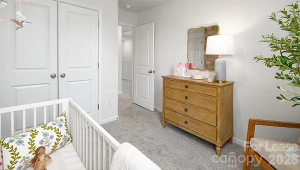 a bedroom with a bed and a lamp on dresser