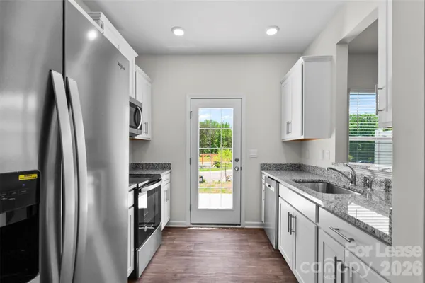 a kitchen with granite countertop a refrigerator stove and sink