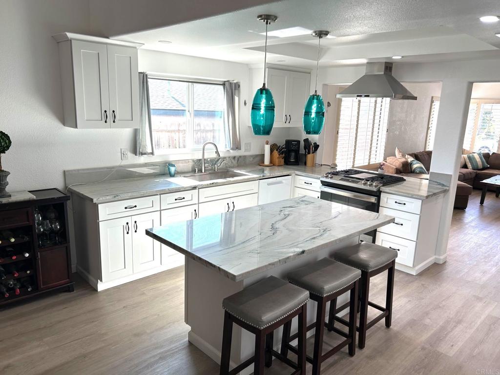 3594 Newland Road Oceanside, CA 92056 - Photo 6 of 44 a kitchen with a stove a sink dishwasher and a dining table with wooden floor