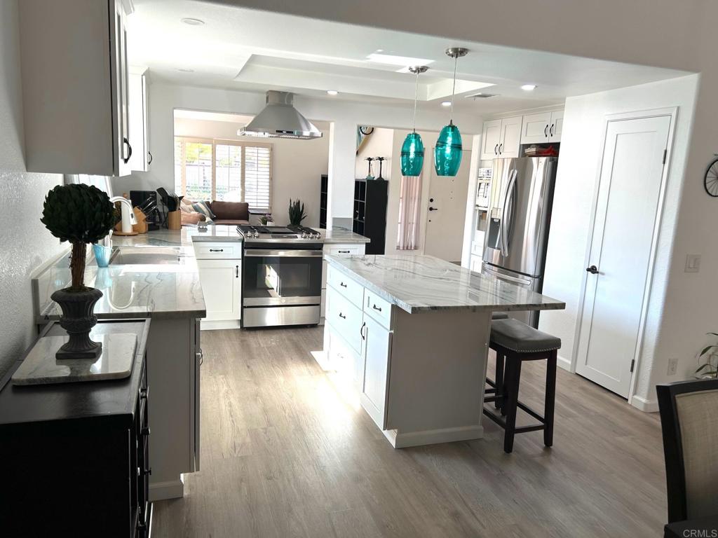 3594 Newland Road Oceanside, CA 92056 - Photo 7 of 44 a kitchen with kitchen island granite countertop wooden floors and white cabinets
