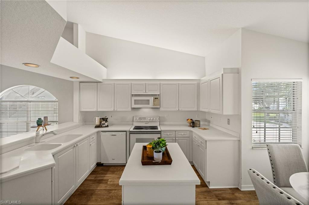 13100 Hamilton Harbour Drive, Unit G11 Naples, FL 34110 - Photo 12 of 32 a kitchen with white cabinets a sink a window and stainless steel appliances