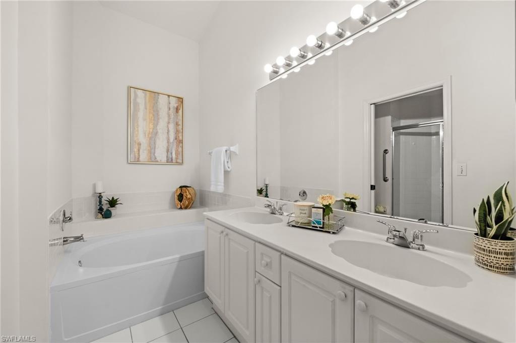 13100 Hamilton Harbour Drive, Unit G11 Naples, FL 34110 - Photo 21 of 32 a bathroom with a tub a double vanity sink and mirror