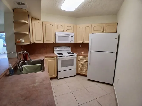 a kitchen with a refrigerator sink and cabinets