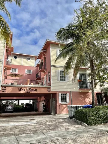 a front view of a building with a garden and trees