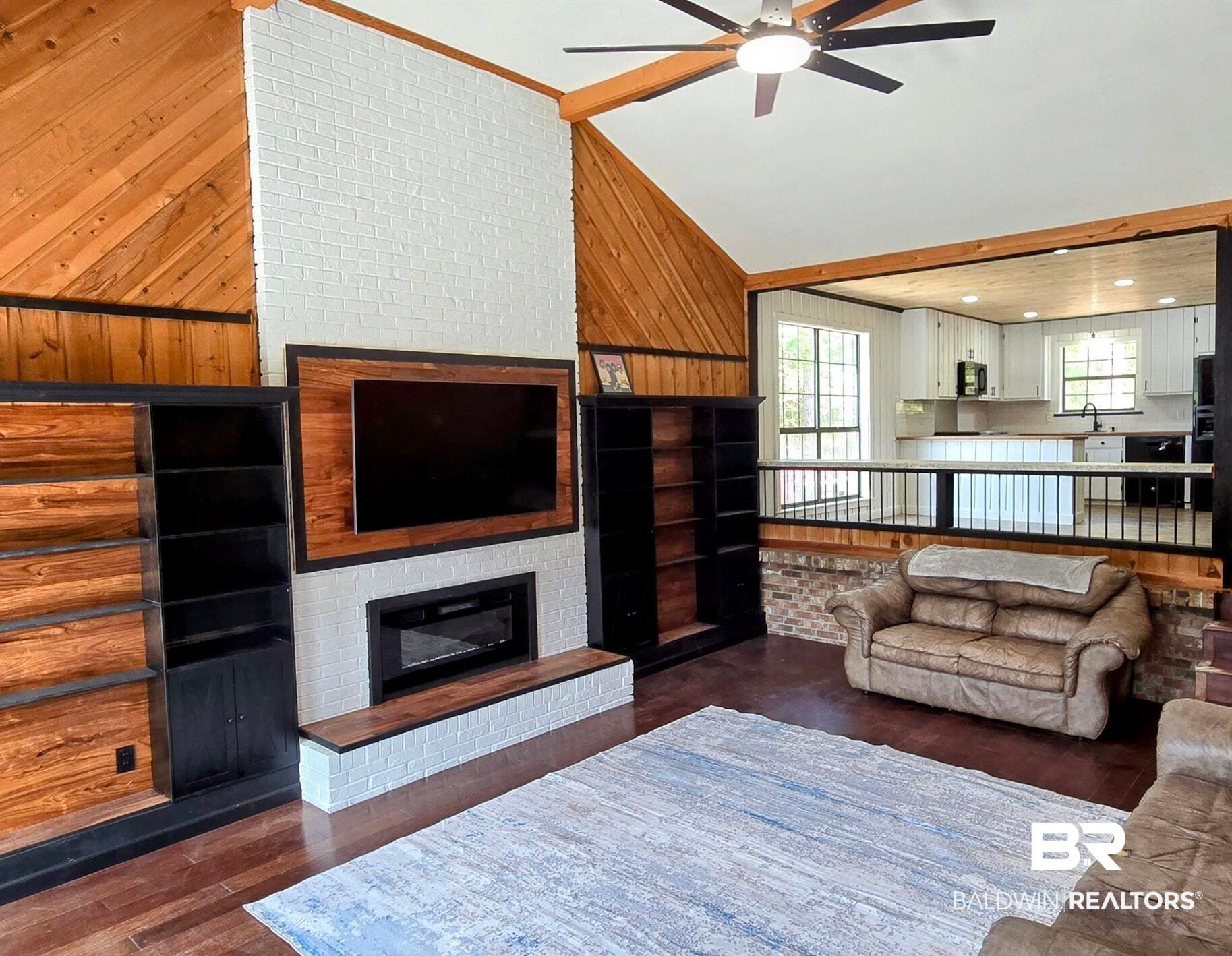 3160 Old Castleberry Road Brewton, AL 36426 - Photo 9 of 36 Vaulted wood-paneled ceilings with a ceiling fan, wood-finish flooring, and a white brick fireplace with a wood mantel