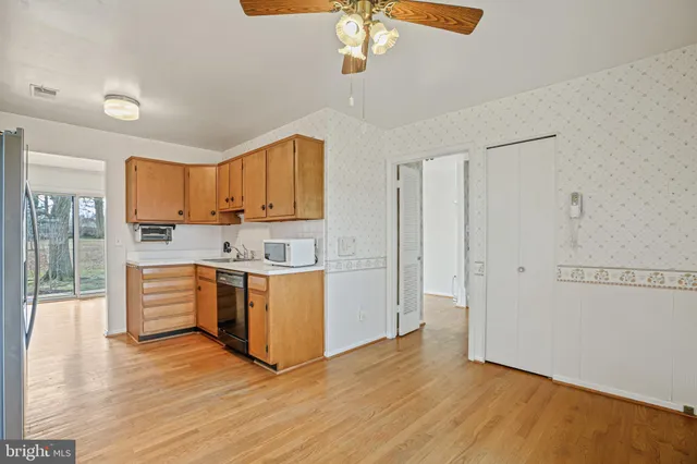 a kitchen with stainless steel appliances granite countertop a refrigerator a stove top oven a sink dishwasher and white cabinets with wooden floor