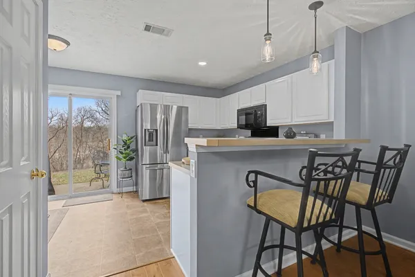 a kitchen with kitchen island a stove a refrigerator and a dining table with wooden floor
