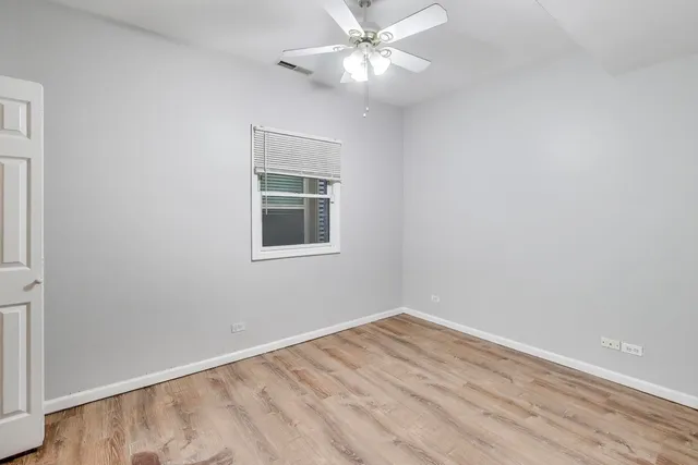 a view of a room with wooden floor and a ceiling fan