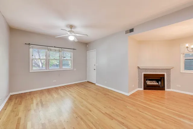 an empty room with windows a fireplace and a ceiling fan