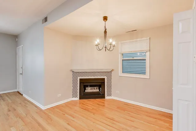a view of empty room with wooden floor fireplace and window